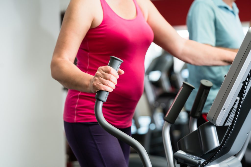 Elderly woman training on cross trainer at the gym