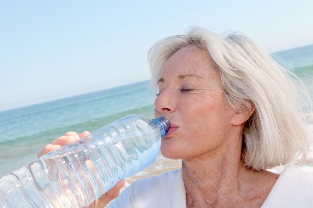 Woman drinking water: natural ways to treat a headache.