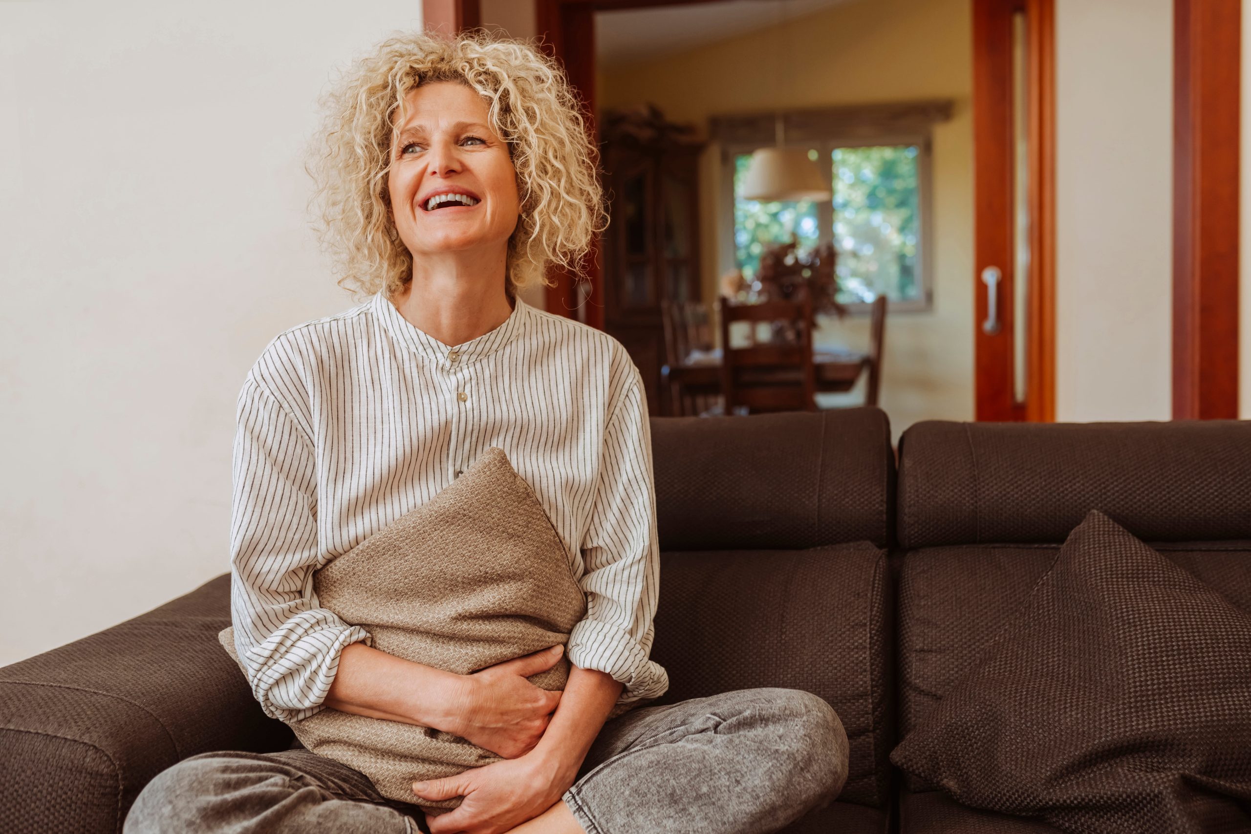 Woman smiling happily on a couch after gut regeneration.