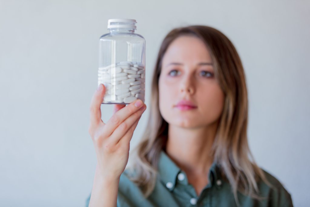 Woman holding a clear jar of pills.