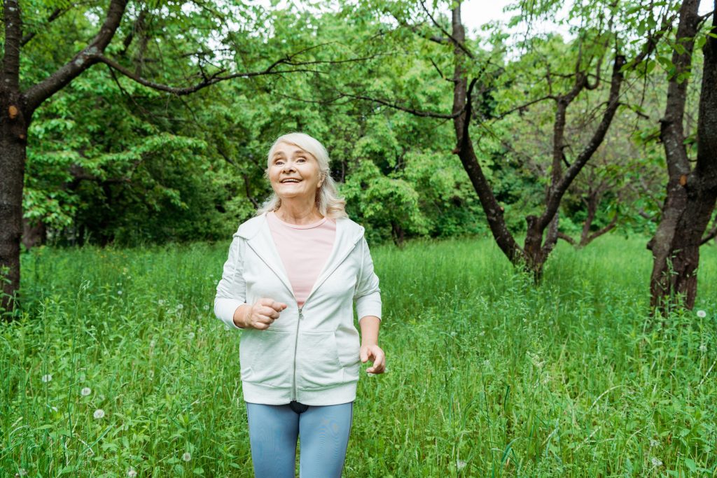 Senior woman running in grassy area
