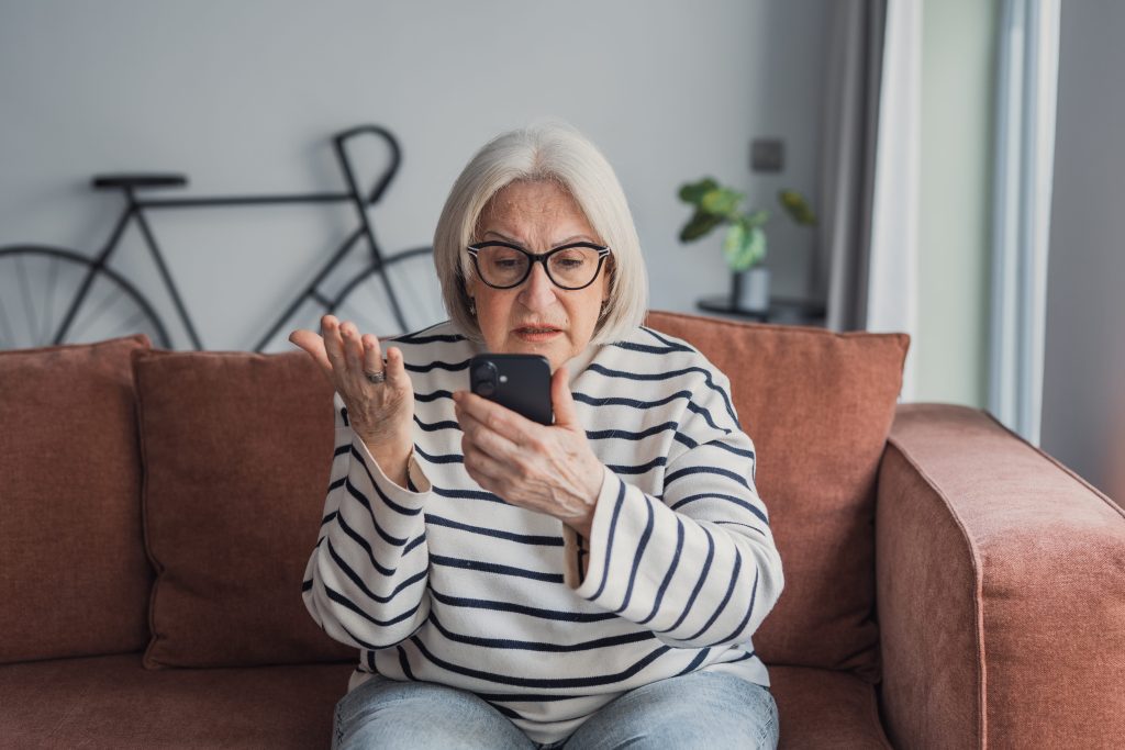 Midlife woman distracted by her phone, a sign of the amygdala hijack that stalls action.