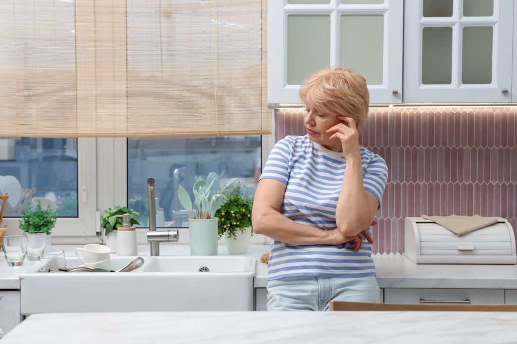 The freeze response in midlife, a woman standing near the dishes yet unable to start.
