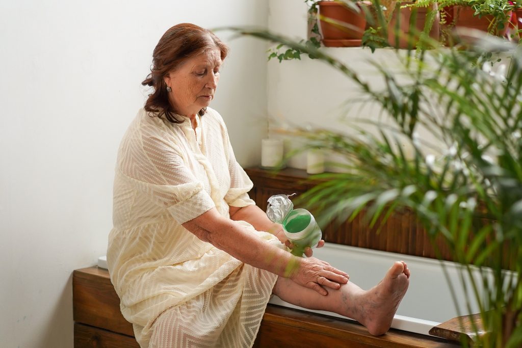 Mature woman rubbing cream on legs`