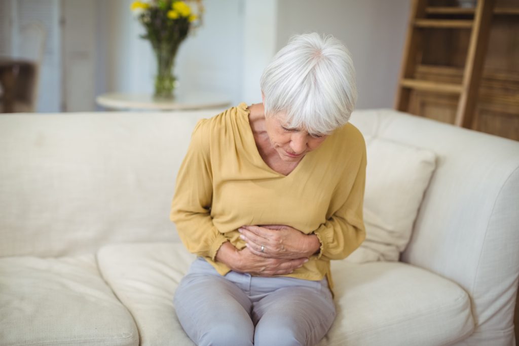 Senior woman clutching stomach due to discomfort