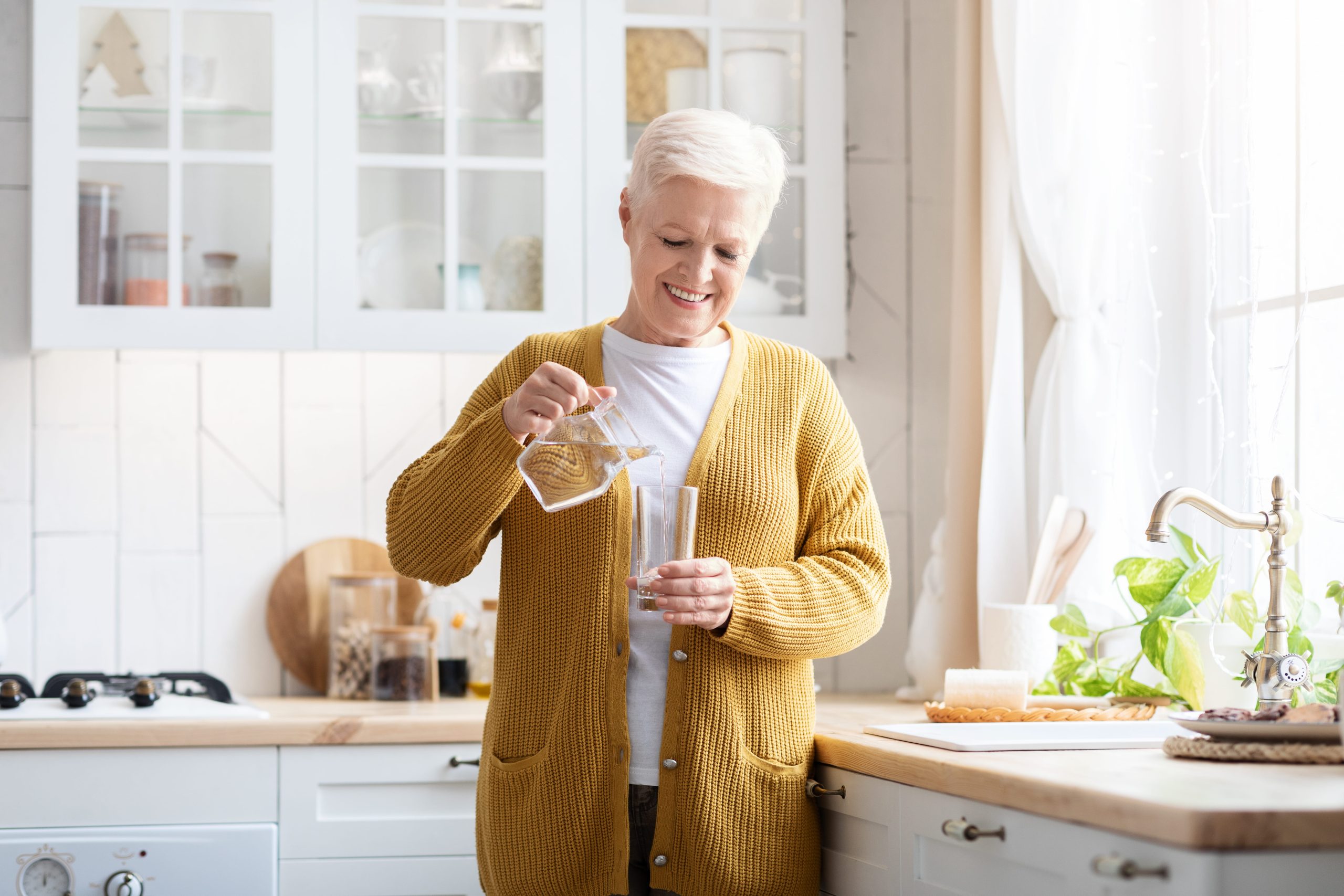 Senior woman pouring drinking water in glass containers