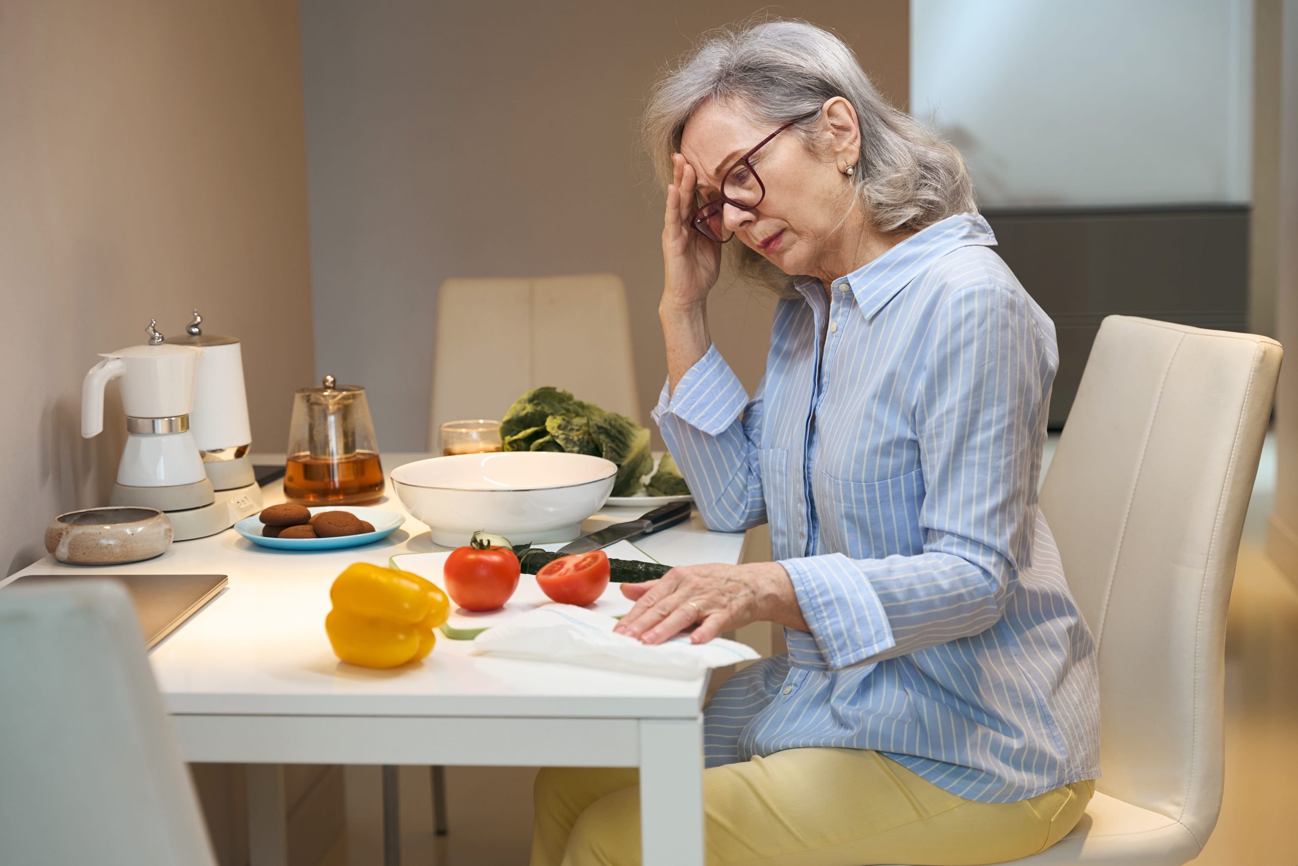 Capable midlife woman standing paused in her kitchen, unable to start a simple task.