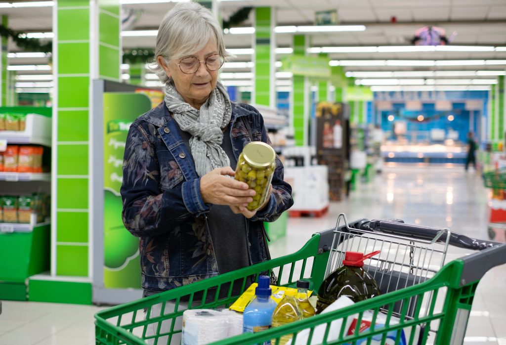 A woman's hands turning a can over to read the ingredient panel, where monosodium glutamate can hide under other names.