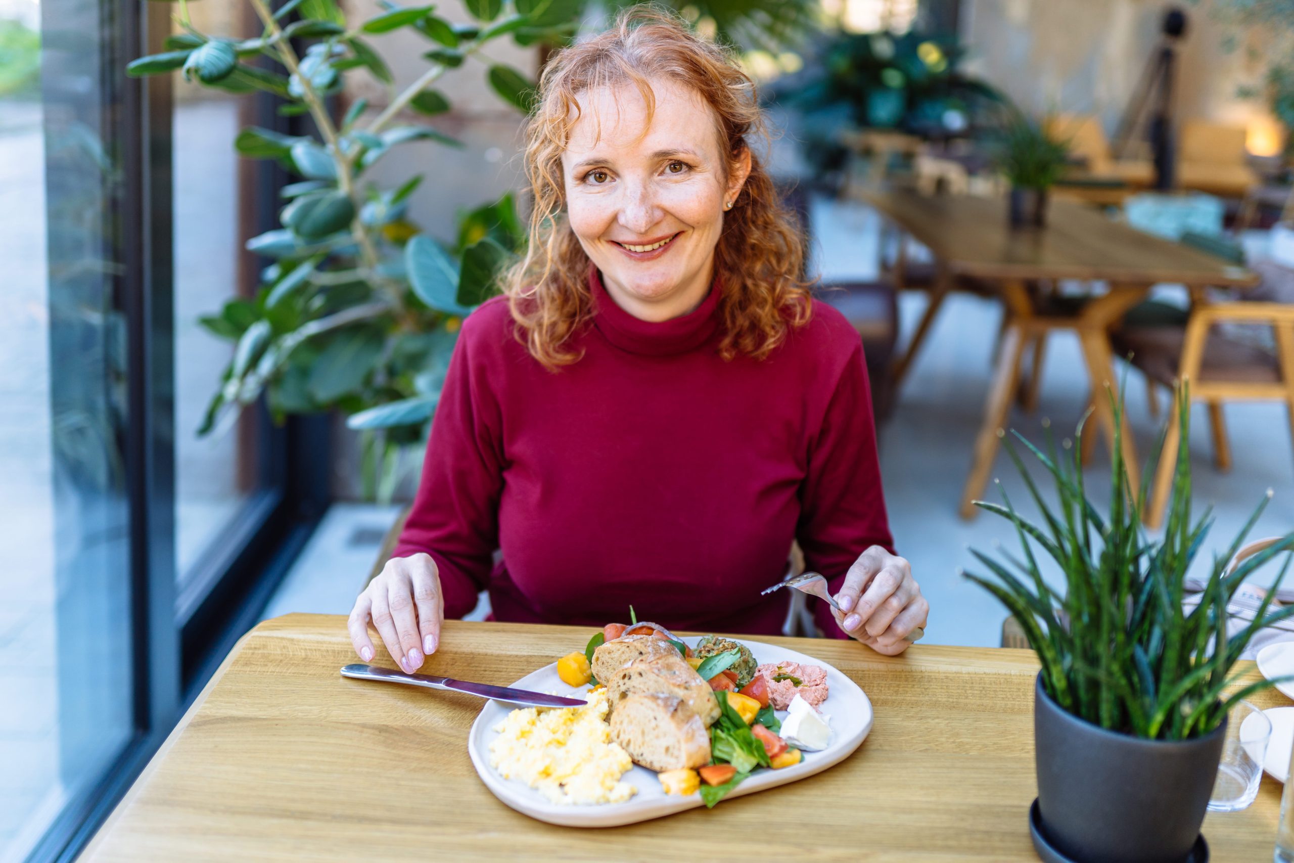 Midlife woman at a table with a plate of meat, considering carnivore diet side effects in perimenopause