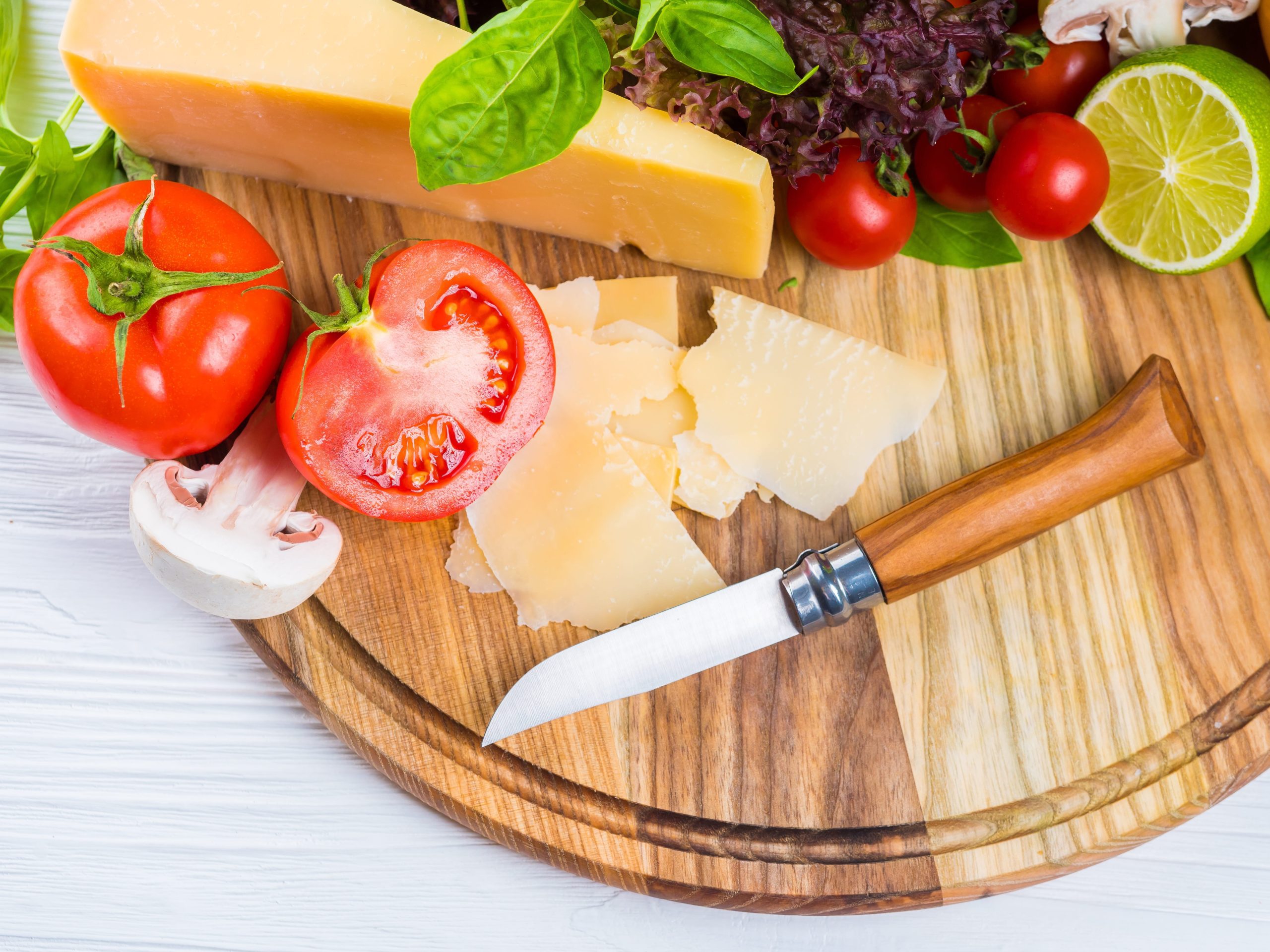 Tomatoes, Parmesan and mushrooms on a wooden board, everyday foods that show what is MSG at its natural source.