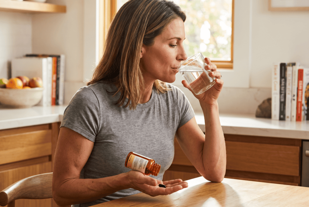 Woman taking an iron supplement with a glass of water